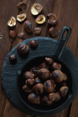 Top view of a frying pan full of roasted chestnuts, close-up