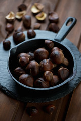 Cast-iron frying pan with roasted chestnuts, selective focus
