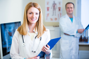 Fototapeta premium Portrait of friendly confident doctors in hospital. Enthusiastic medical staff at work. Female doctor with stethoscope looking at the camera. 