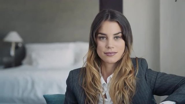 Portrait of young business woman in a hotel room looking at camera. Dolly shot.