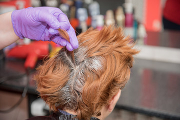 A hairdresser coloring hair of a woman. Selective focus.