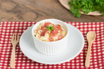 Macaroni and cheese with ham on wood table.