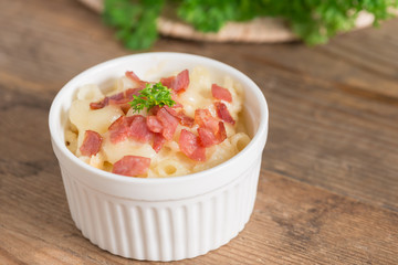 Macaroni and cheese with ham in white bowl.