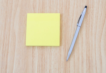 Blank yellow notepad with pen on office wooden table