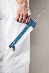 Workman Hand holding Caulking Gun for Silicone Sealant - 102570721