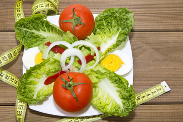 plate of salad and tape measure on wood