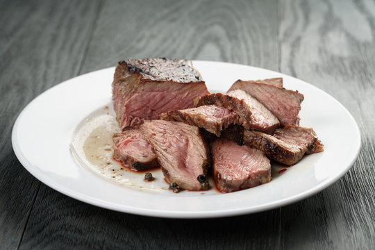 sliced beef steak on white plate on wood table
