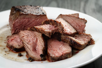 sliced beef steak on white plate on wood table