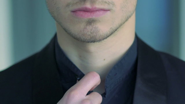 Close up of elegant man tucking dark shirt. Slow motion