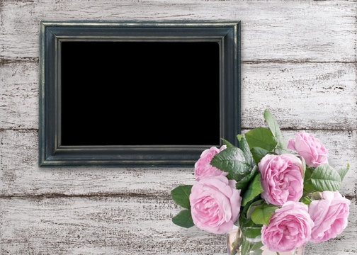 Roses and photo frame on background of shabby wooden planks