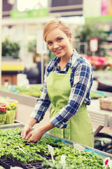 happy woman taking care of seedling in greenhouse
