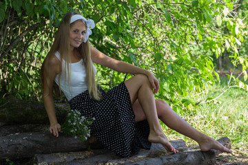 Young Caucasian woman sitting on wood and holding a bunch of flowers