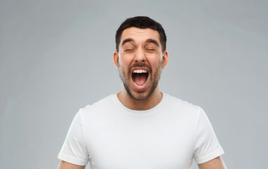 crazy shouting man in t-shirt over gray background