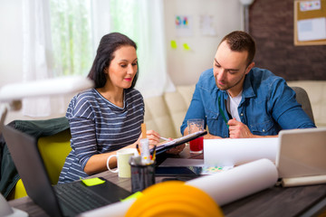Obraz premium Smiling architect looking the architectural plans in office.