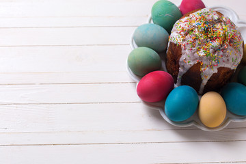 Colorful Easter cake and Easter eggs on plate  on white wooden b