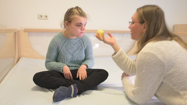 Disability a disabled child playing with her toys / Disability a disabled child playing with her toys with help from a special needs carer