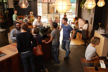 Customers at the counter of cafe being helped by barista