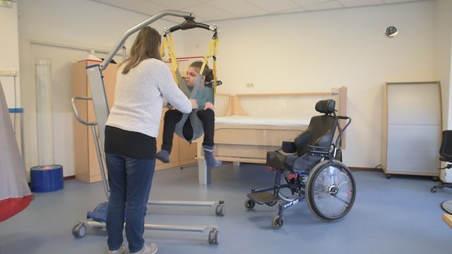 Disability a disabled child being cared for by a carer / Disability a disabled child being cared for by a special needs carer using specialist lifting equipment