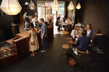 Modern coffee shop with baristas and various customers ordering 