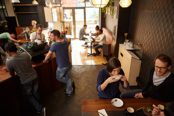 Modern coffee shop with contented customers sitting and standing