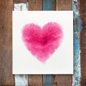 Heart shape of watercolor brushes on canvas frame with wooden ba