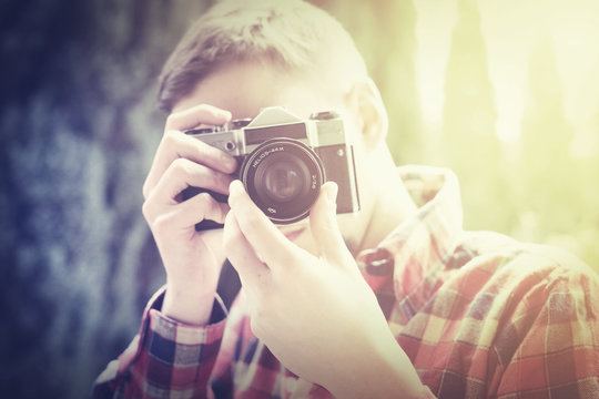 Hipster in flannel shirt taking photo with oldshool, vintage, analog camera. - retro filter