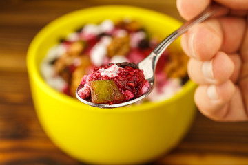 Hand holding spoon with sweet cottage cheese dessert, raspberry jam, candied, blurred background, selective focus
