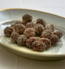 Hausgemachte Kakao Pralinen mit Kokosraspeln auf weißem Teller