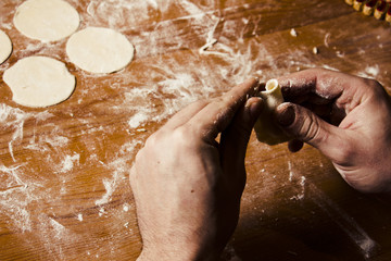 Man's hands preparing dough for ravioli, tortellin in vintage toningi. Making baking.