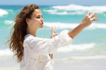 Fototapeta na wymiar Beautiful young woman taking selfie at the beach