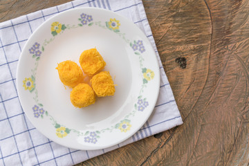 Sweet egg floss in a dish with fabric on wood background kind of Thailand traditional dessert in thai name of Foi Thong
