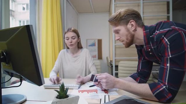 Passive aggressive girl at the computer, a man helps make purchases online