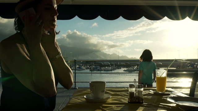 Woman answering her phone in the restaurant and her son walking, steadycam shot
