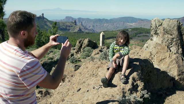 Father doing photo of his son on smartphone in the mountains
