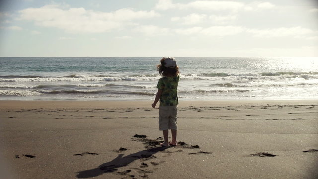 Young boy dancing on the sandy beach and having fun, steadycam shot
