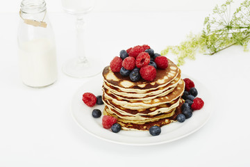 Pancakes topped with fruit in white studio
