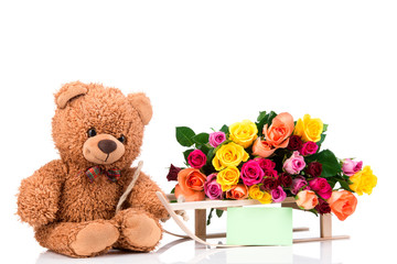 Bunch of roses and a teddy bear on white background