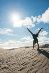 Young woman handstanding on the sand dunes of Te Paki, New Zealand