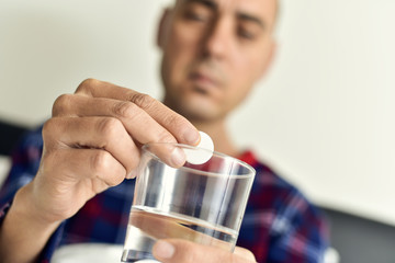 man putting an effervescent tablet into a glass with water