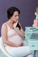 Worried pregnant woman at desk 