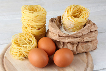 pasta with eggs and flour on wooden cutting Board on white wooden table