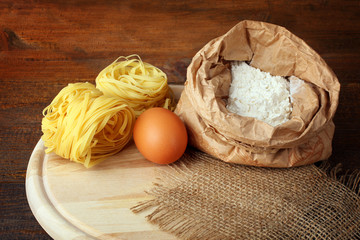 pasta with eggs and flour on wooden cutting Board on white wooden table