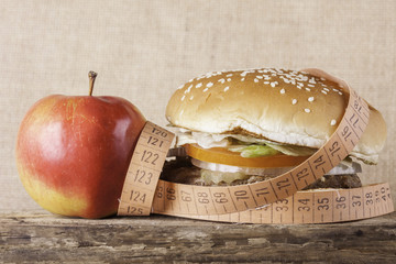 hamburger and apple with meter, diet concept on woodes surface