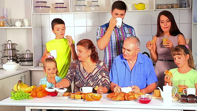 Big happy family have breakfast at kitchen. Three generations of grandparents of their children and grandchildren in  kitchen eating breakfast at home .