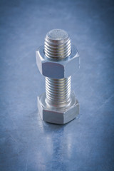 Steel threaded bolt and nut on metallic background construction 