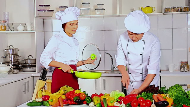 Chef man and woman professional in hat cooking vagetable . Used tripot.