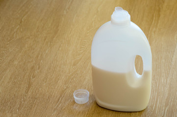 Liquid detergents bottle with it's cup next to it