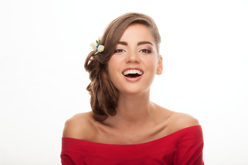 Fototapeta premium Closeup portrait of laughing young cute brunette woman with flower headpiece and cool makeup in read blouse looking into camera posing on white studio background
