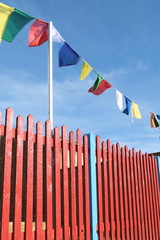 Red wooden fence with party flags against blue sky