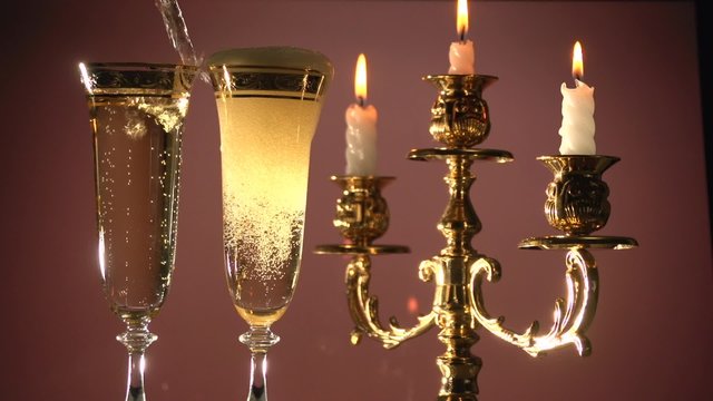 Champagne. Two flutes with champagne by candlelight in a golden candelabrum. 